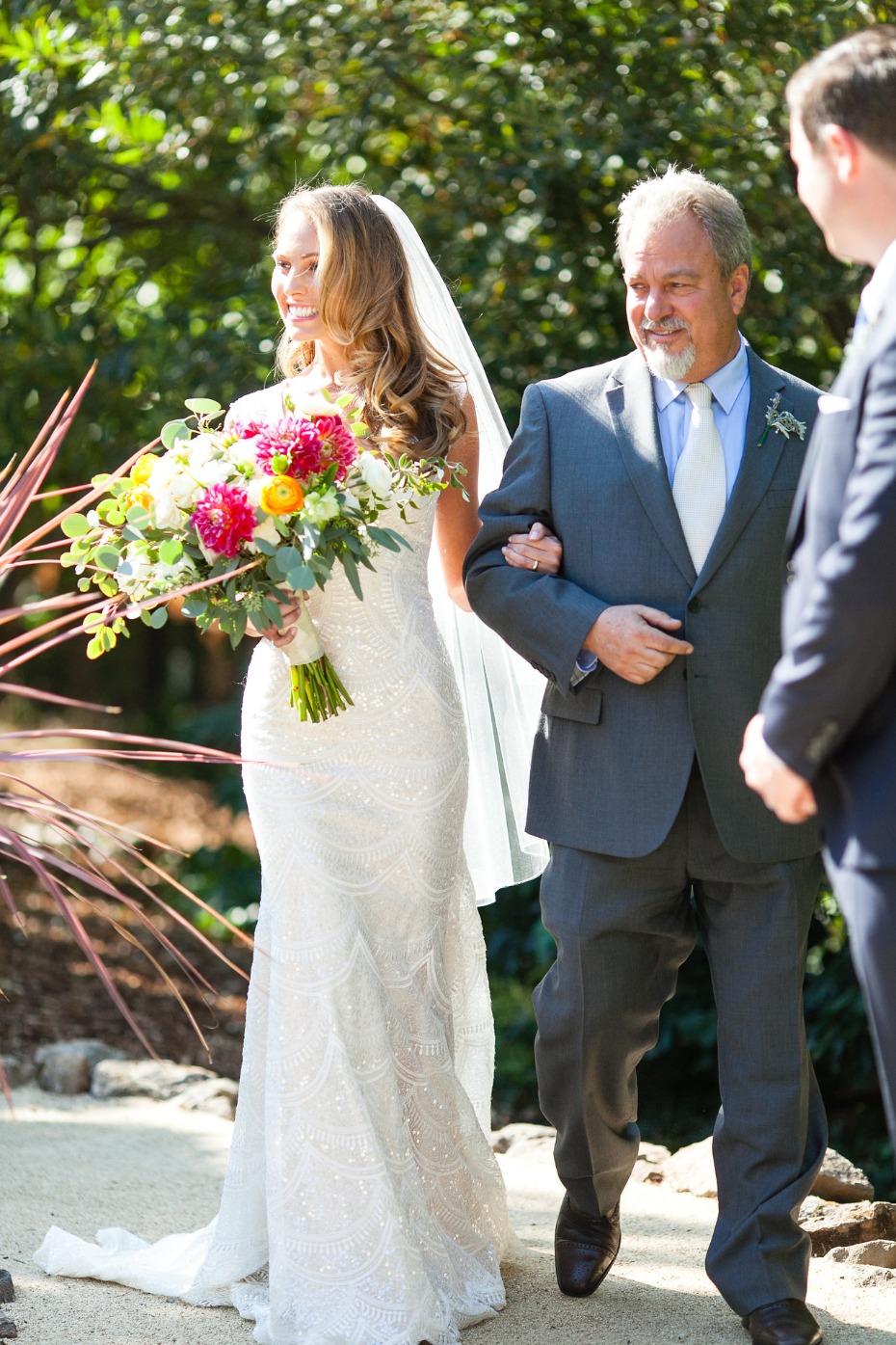 Bride walks down aisle with her father at outdoor wedding