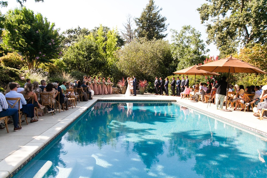 Outdoor wedding ceremony beside a pool in a lush garden