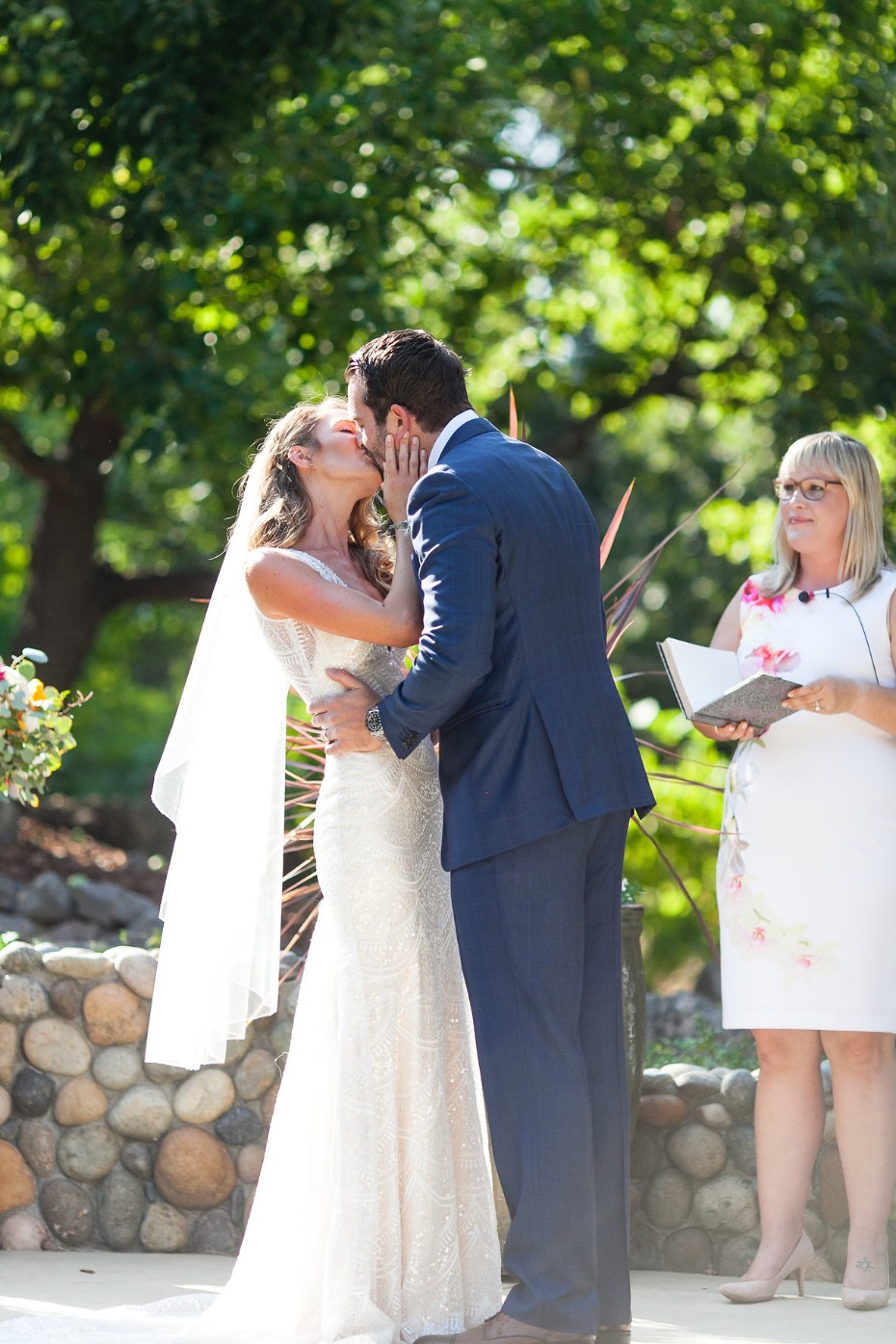 Newlyweds share a kiss during outdoor wedding ceremony
