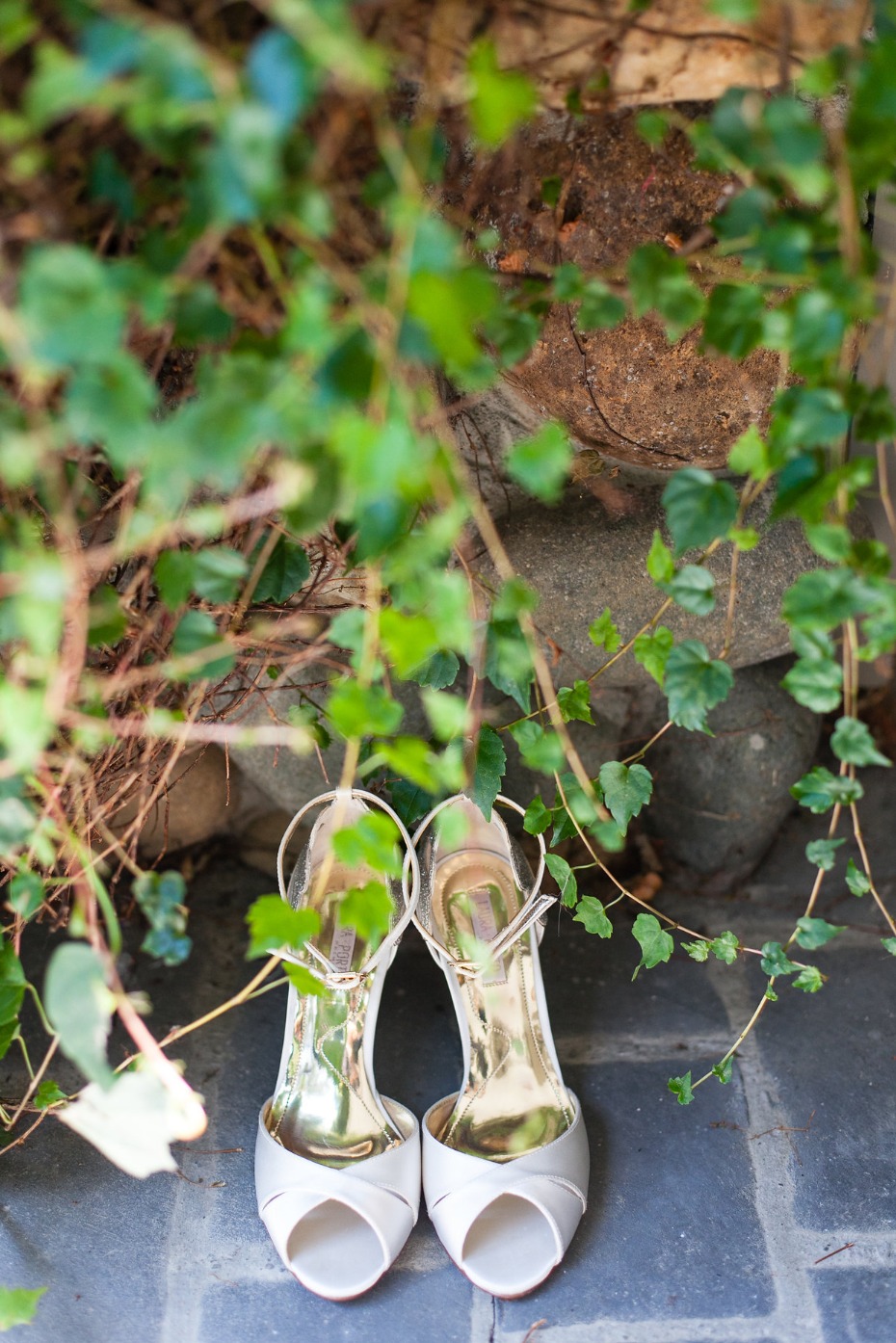 Elegant white wedding shoes outdoors with greenery