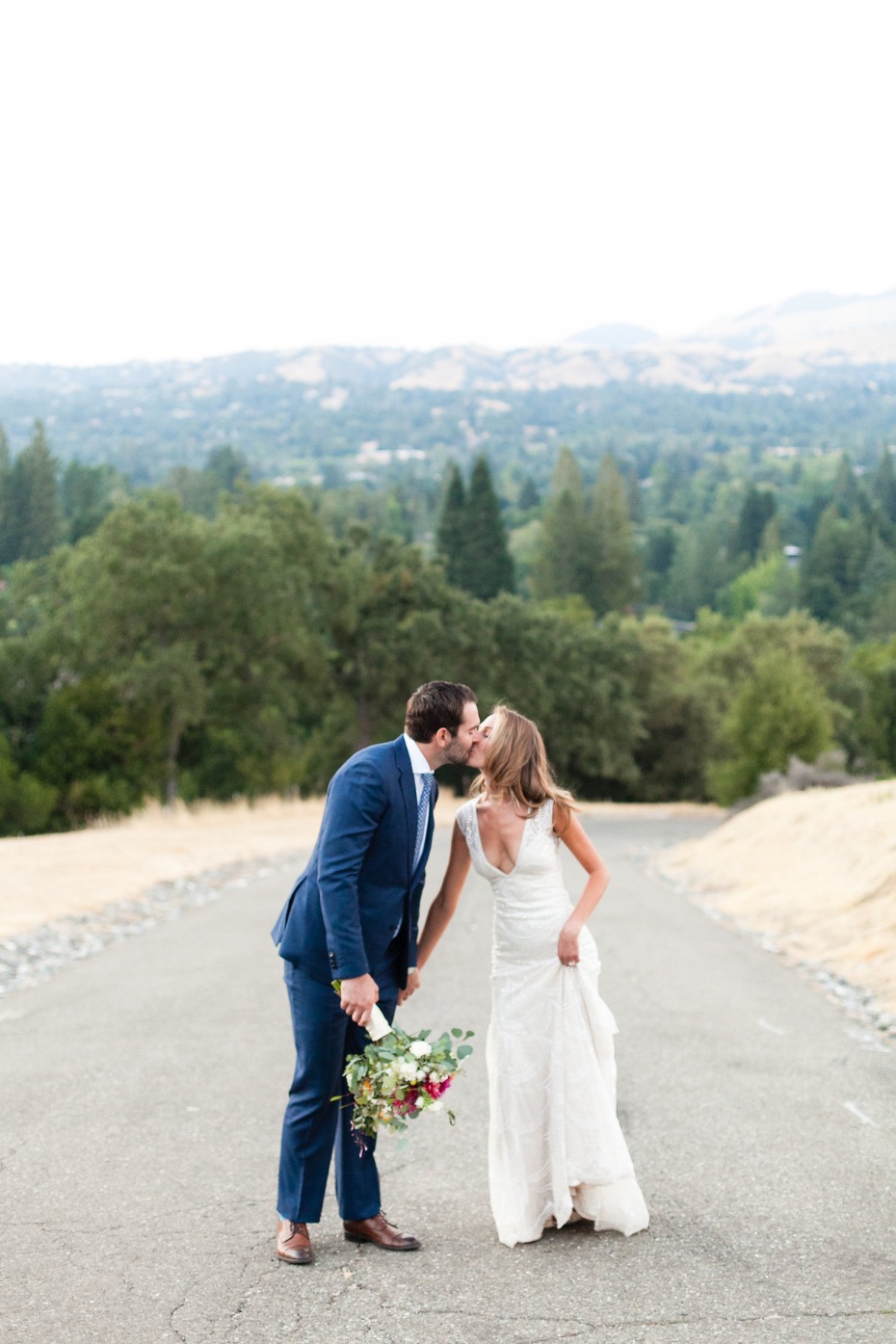 Newlyweds share a kiss on a scenic road wedding day