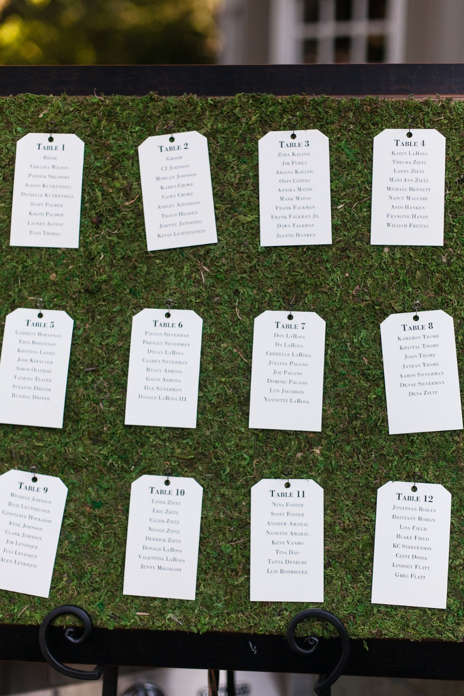 Wedding seating chart with table assignments on moss board