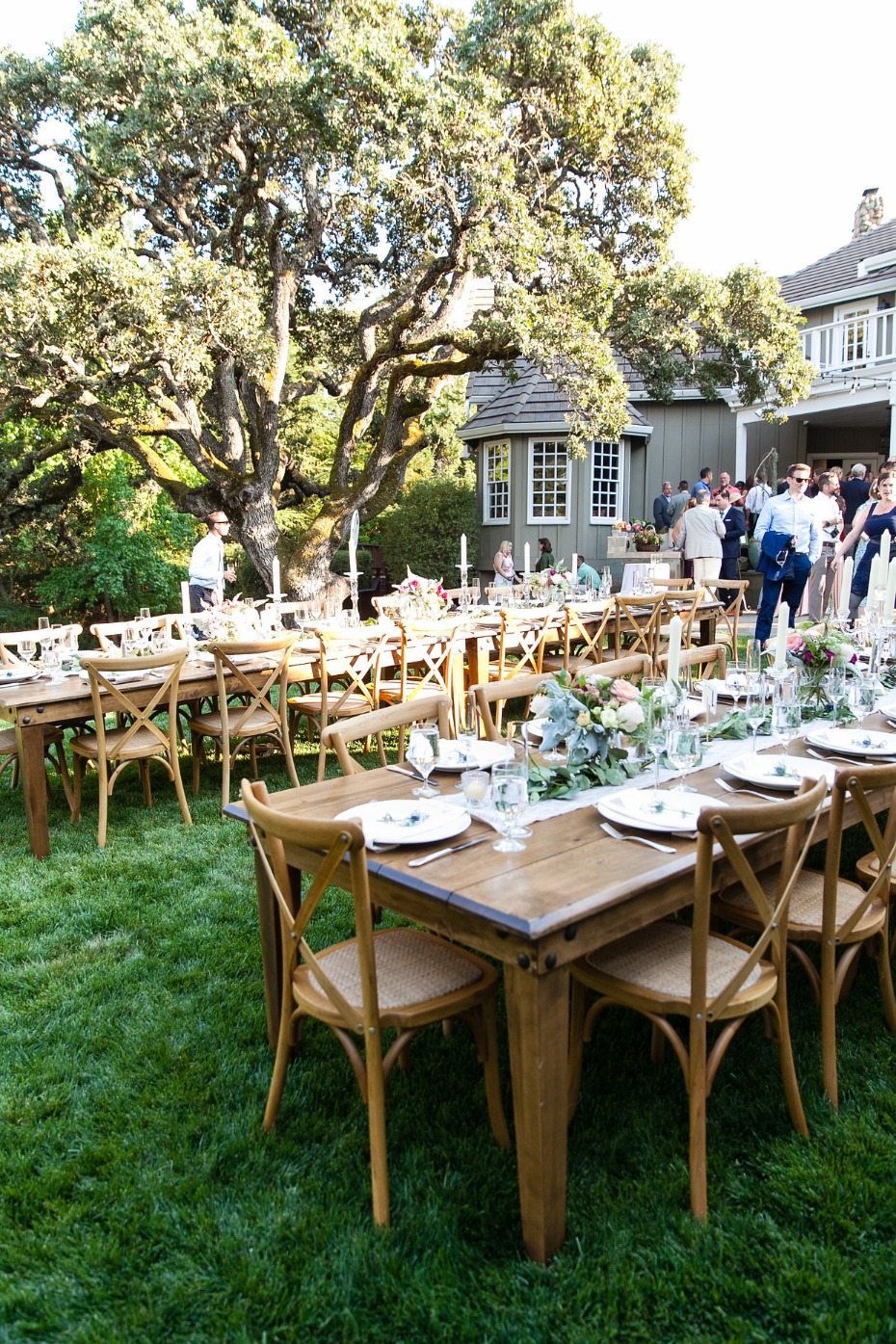 Outdoor wedding reception on a green lawn with wooden tables