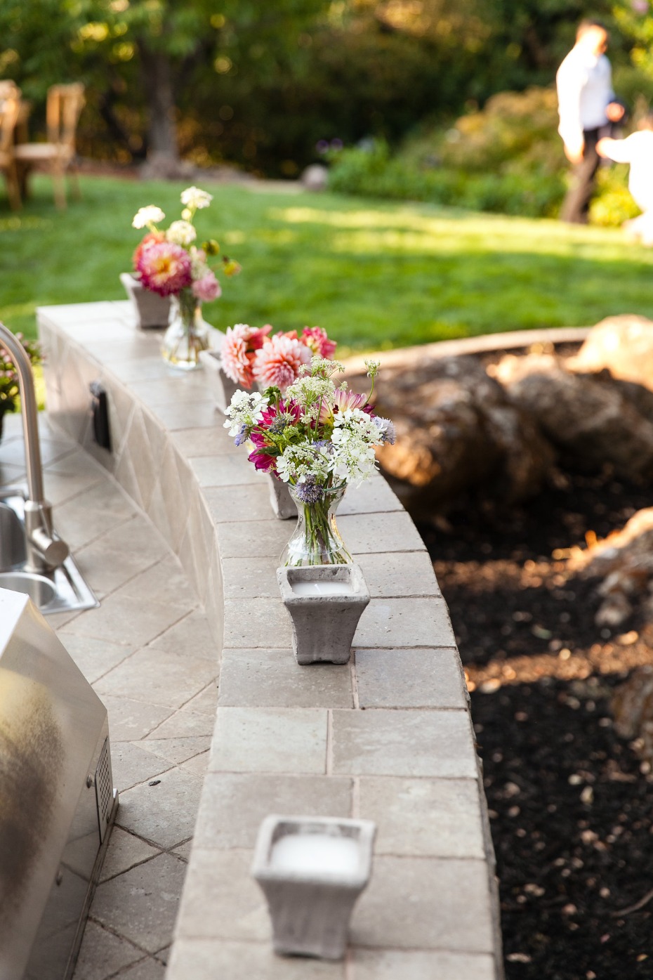 Flowers in vases on a stone outdoor kitchen counter