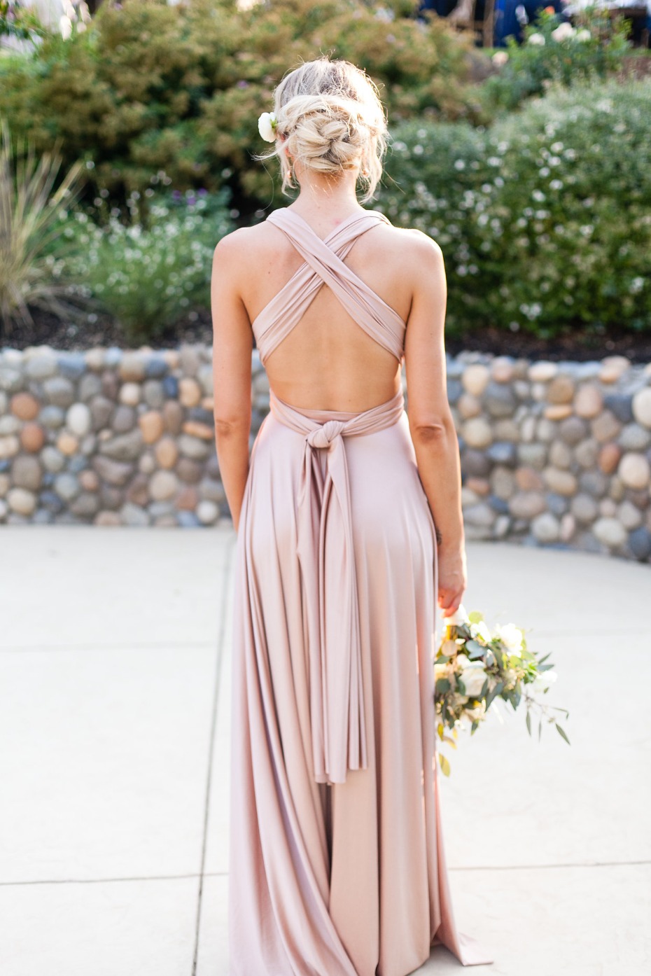 Woman in blush wrap dress at outdoor wedding venue
