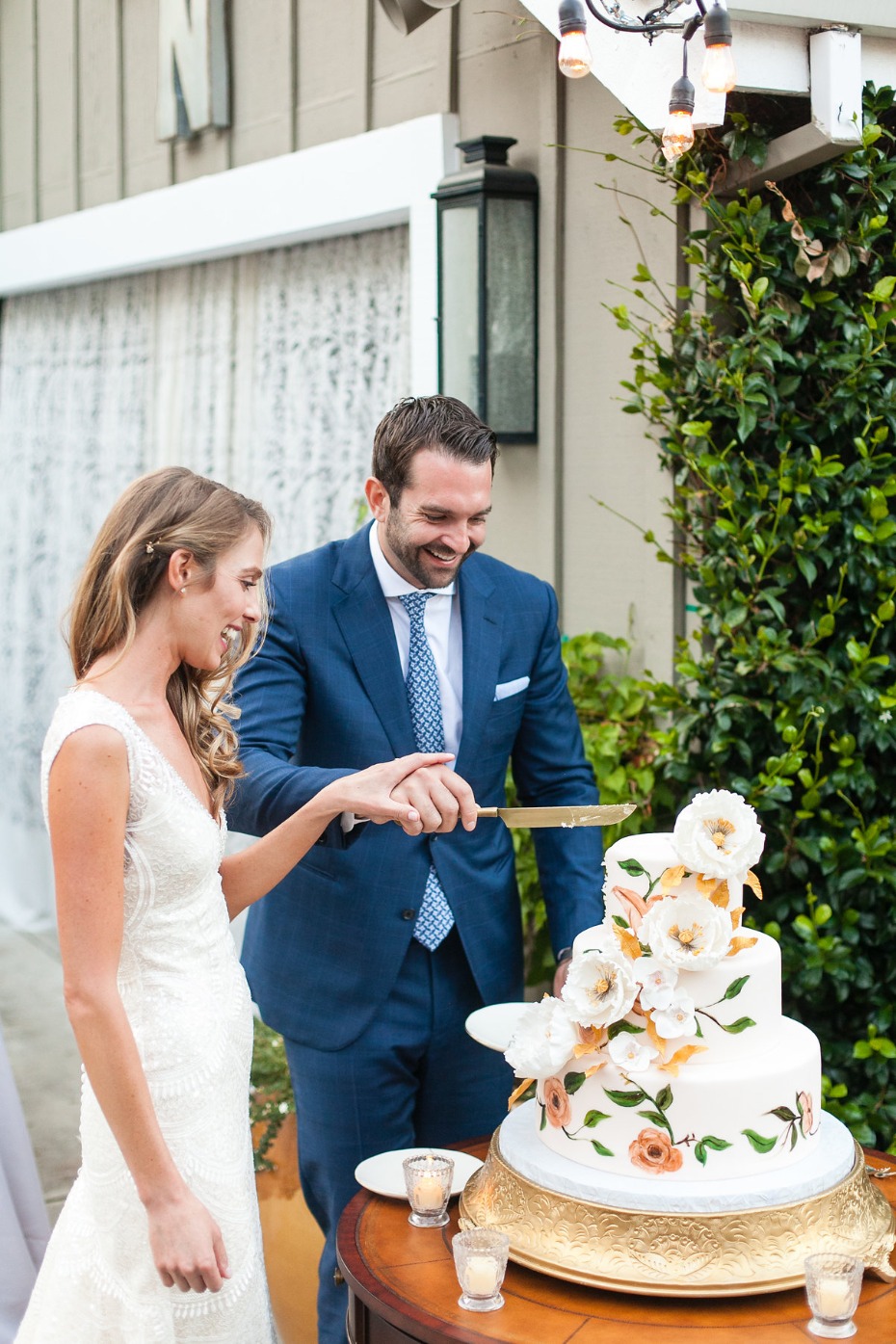 Bride and groom joyfully cutting their elegant wedding cake