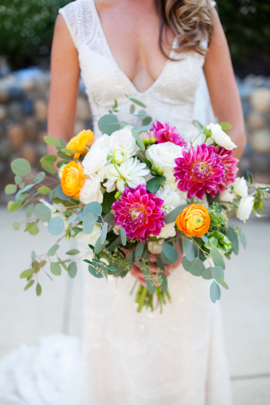 Bride holding colorful dahlia and rose wedding bouquet