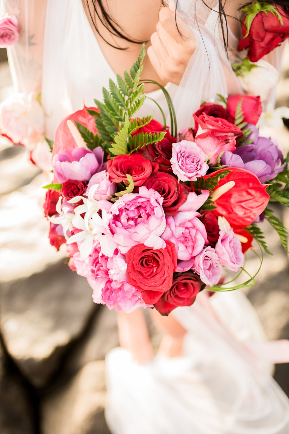 Bride holding colorful red and pink wedding flower bouquet