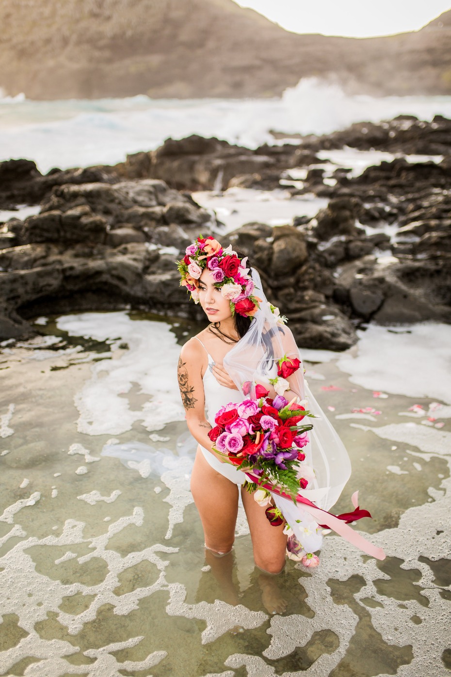 Woman with flowers and veil standing in the ocean water
