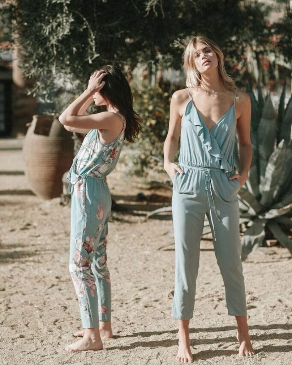 Two women in stylish matching blue jumpsuits outdoors