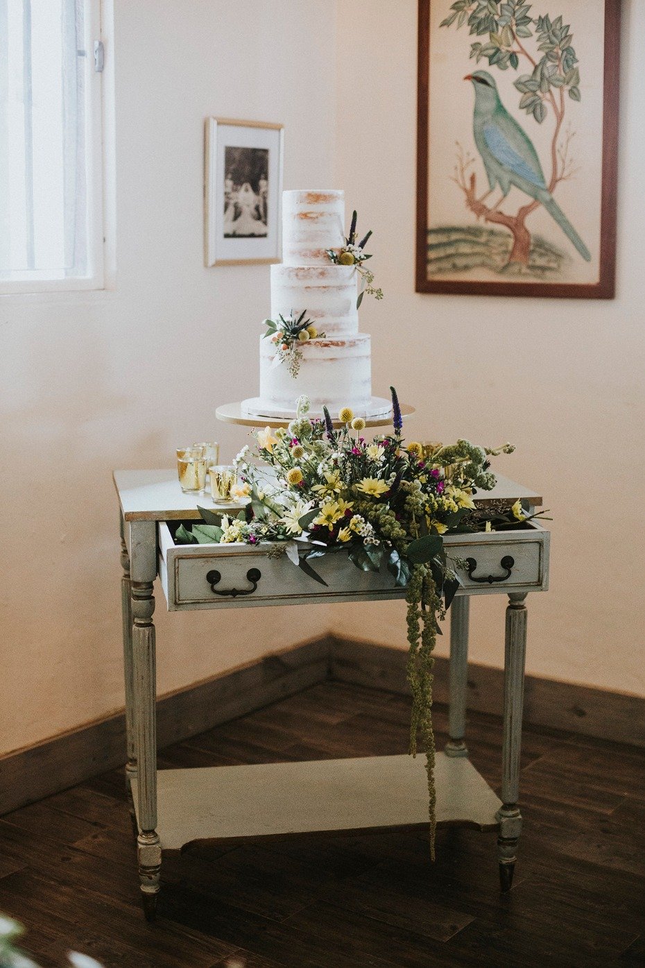 nearly naked wedding cake with vintage flower filled cake table
