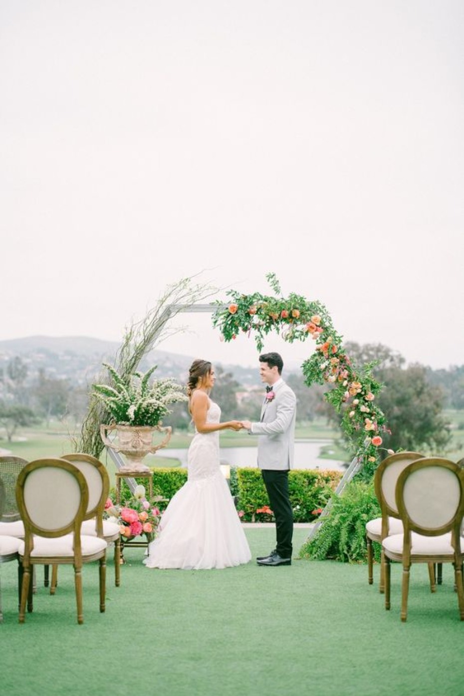 Bride and groom exchanging vows at floral wedding arch