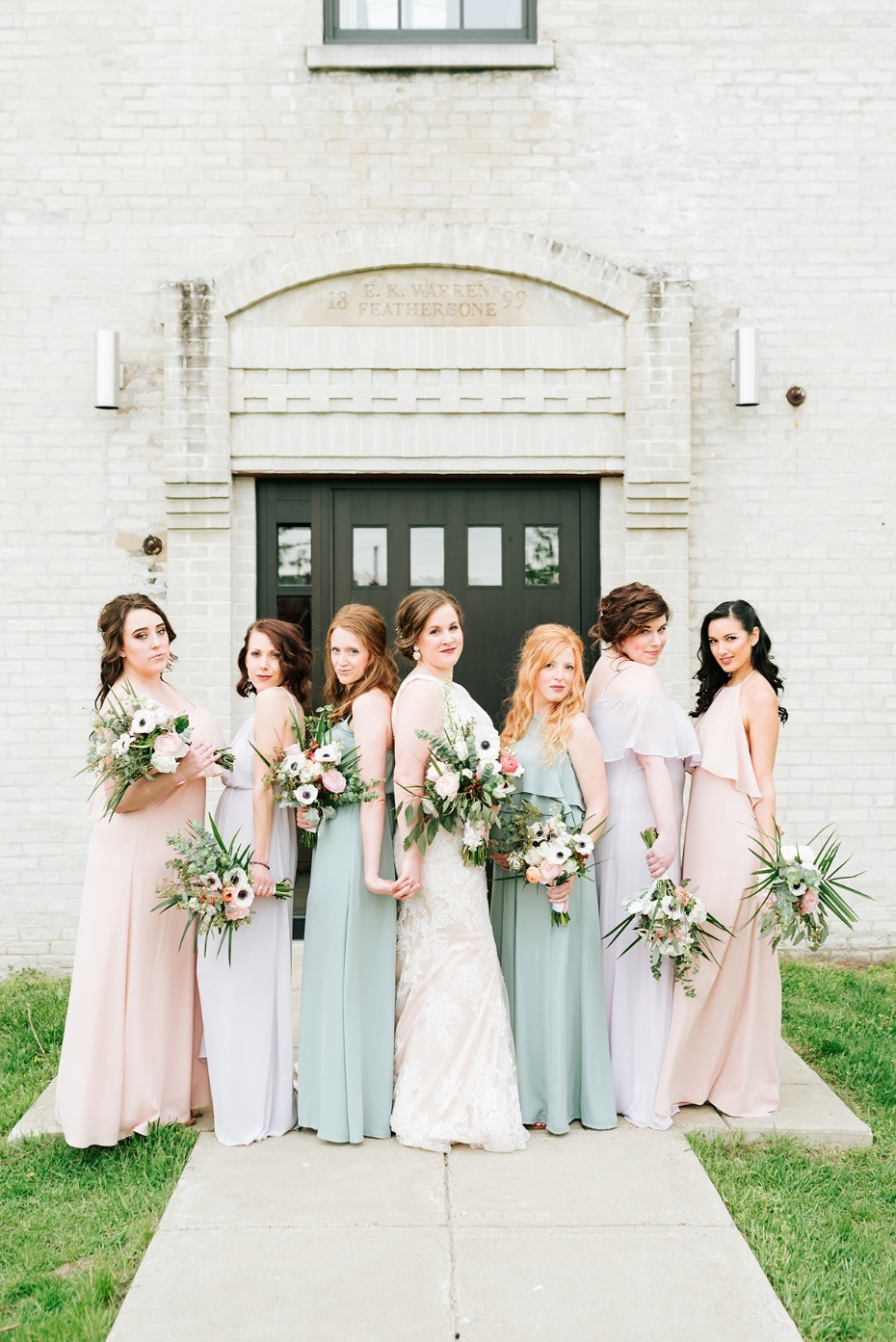 Bridesmaids in pastel gowns pose for wedding photo