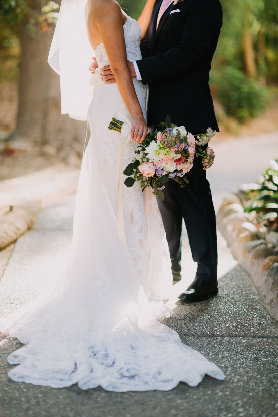Bride and groom embrace with floral bouquets wedding day