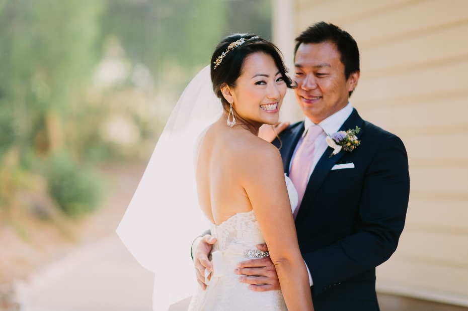 Smiling Asian bride and groom embrace on their wedding day