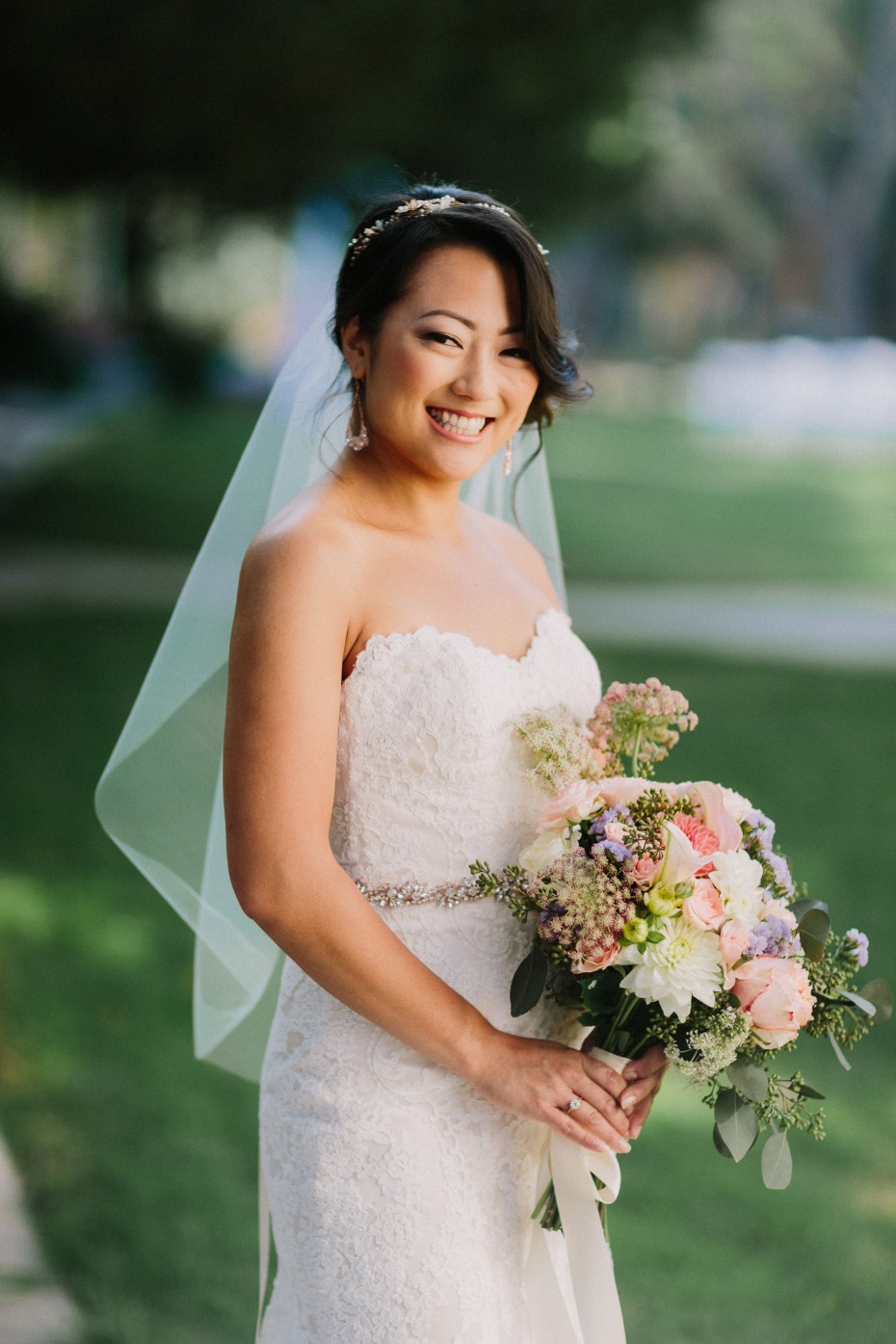 Smiling bride wearing a white wedding dress with floral bouquet