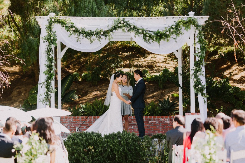 Wedding ceremony under a floral decorated arbor outdoors