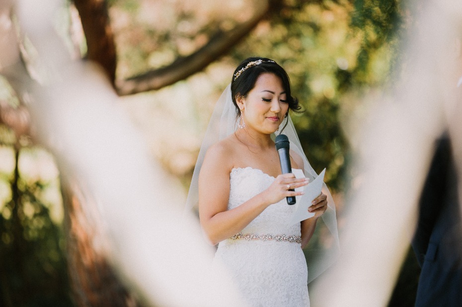 Bride giving speech at outdoor wedding ceremony, holding microphone
