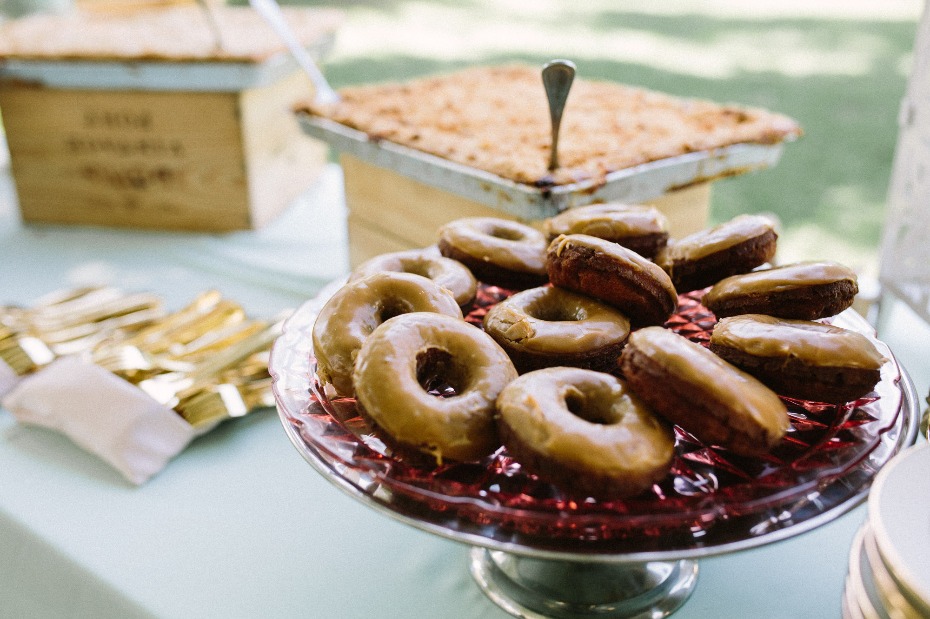 Delicious glazed donuts on a tiered dessert stand with dessert in the background