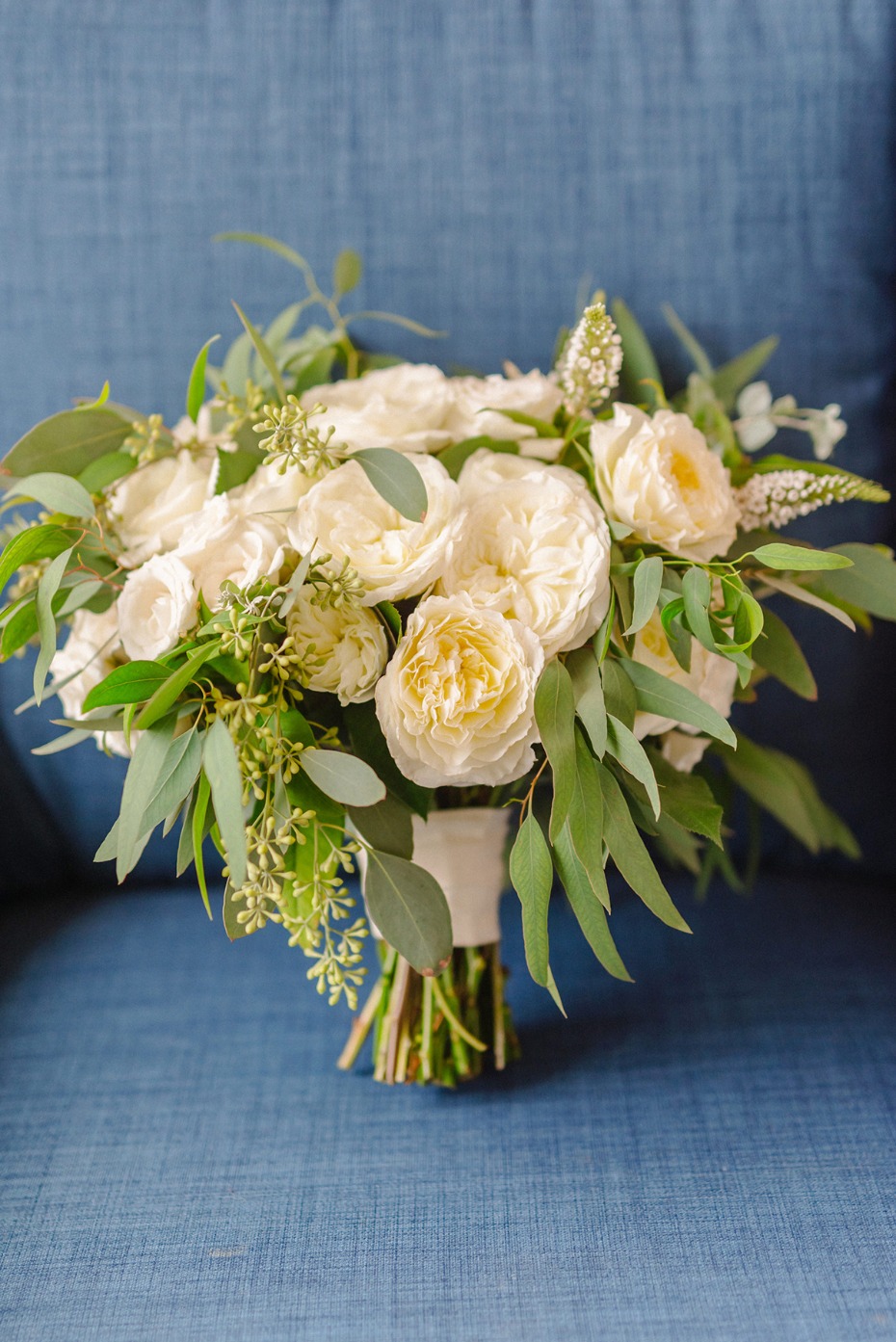 Elegant white rose bouquet with greenery on blue background