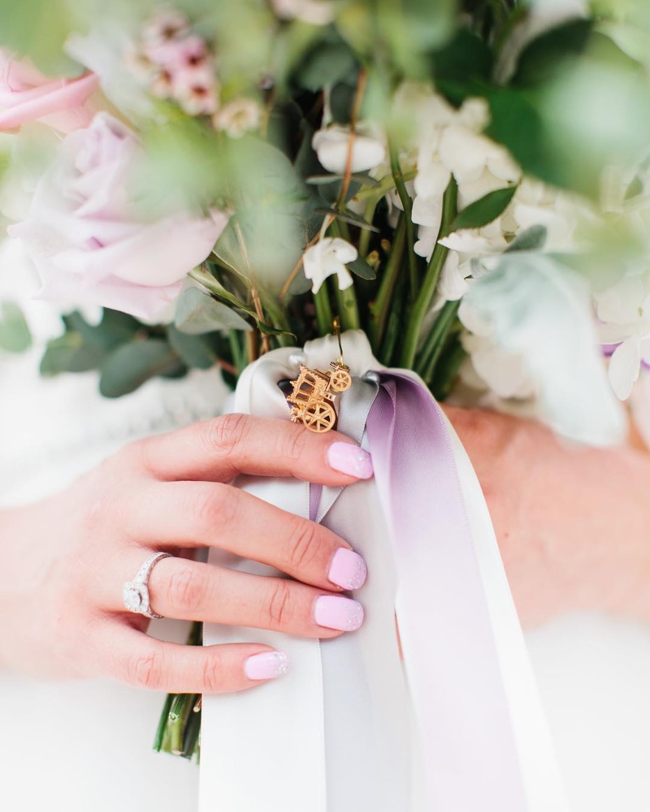 Bride holding pastel bouquet with carriage charm detail