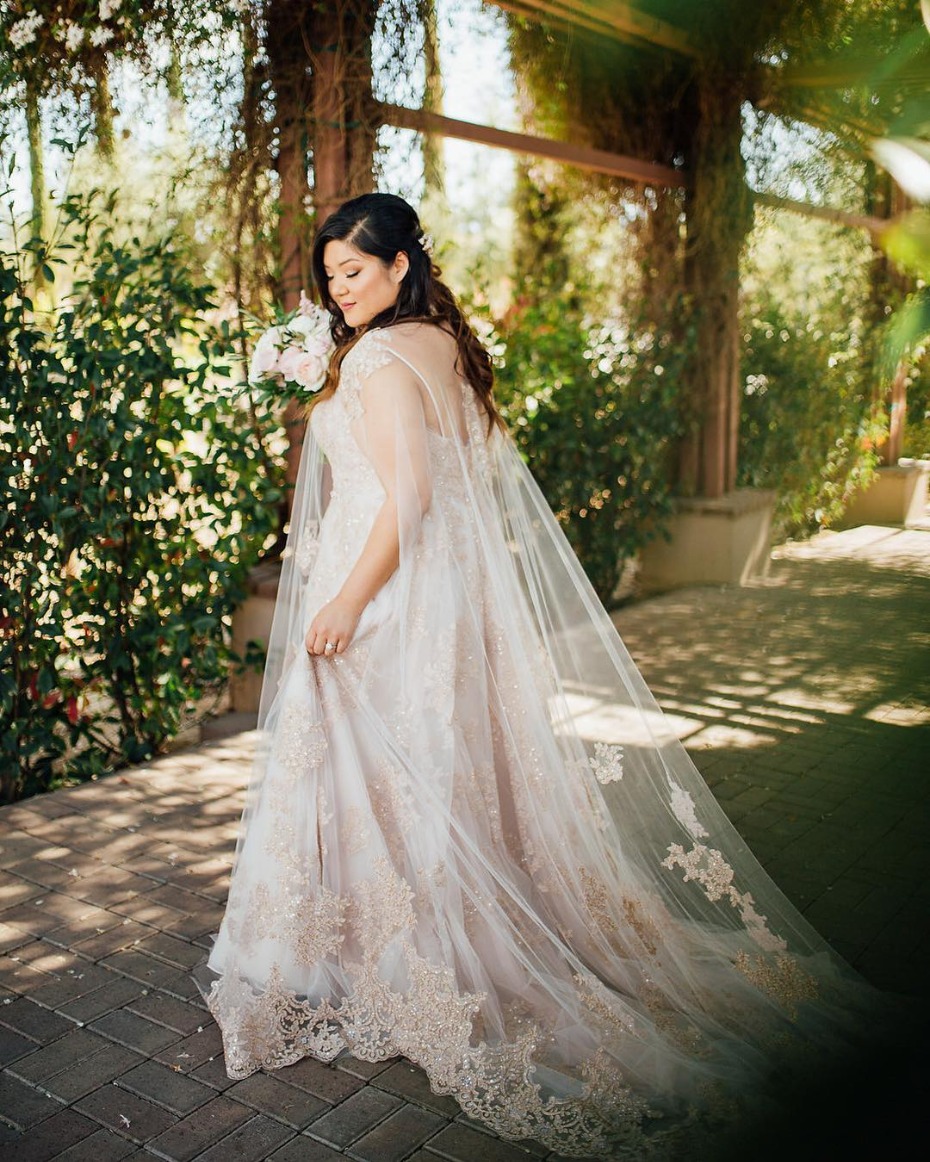 Elegant bride in a lace wedding dress with a long flowing cape