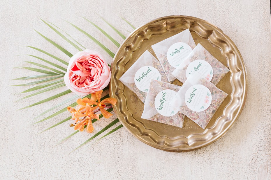 Birdseed packets on a brass tray with pink flowers and tropical leaves