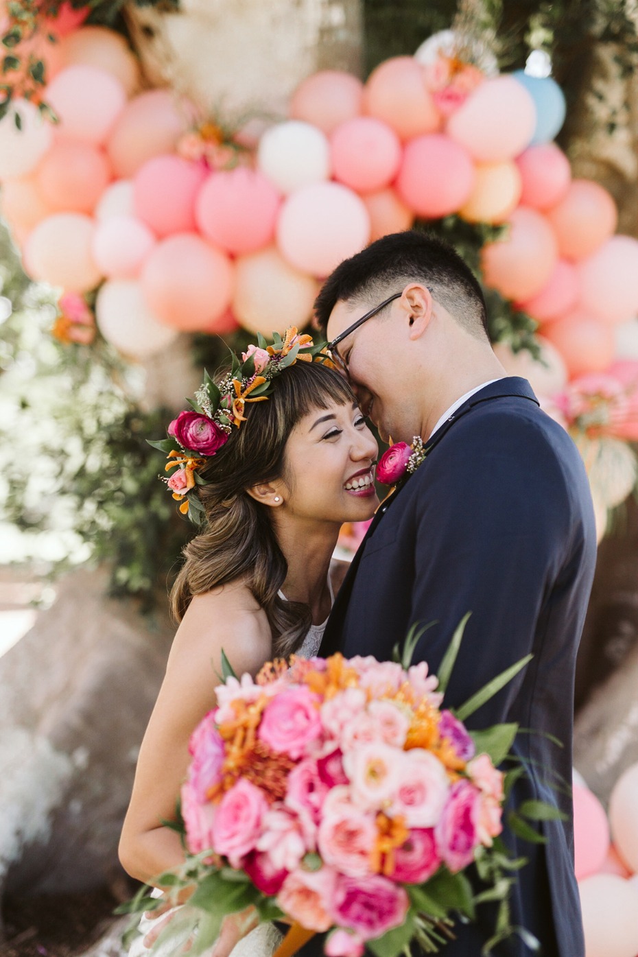 Happy couple embraces with a floral bouquet, balloons in the background