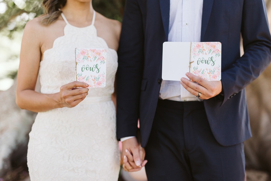 Bride and groom holding vow books at their outdoor wedding ceremony