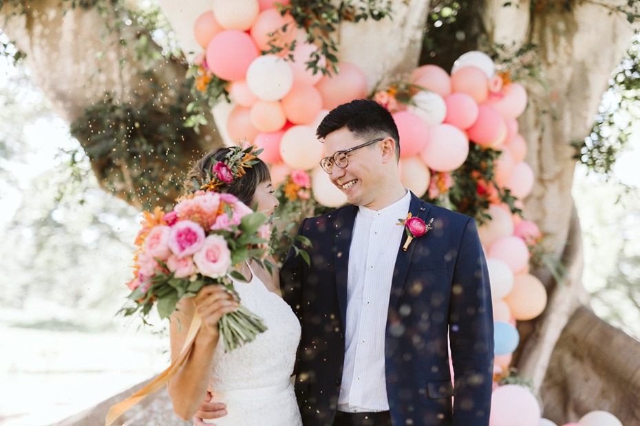 Happy newlywed couple smiling at their outdoor pastel wedding ceremony