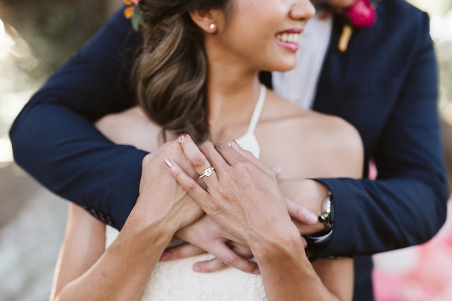 Happy bride smiles while being embraced, engagement ring shines