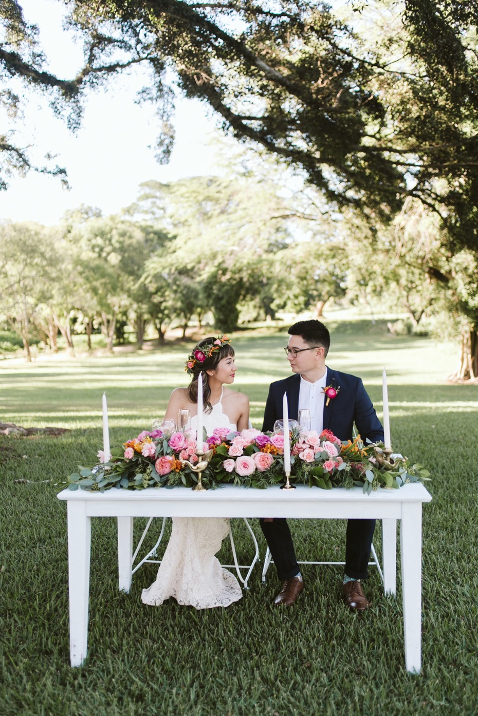 Bride and groom at floral sweetheart table outdoors