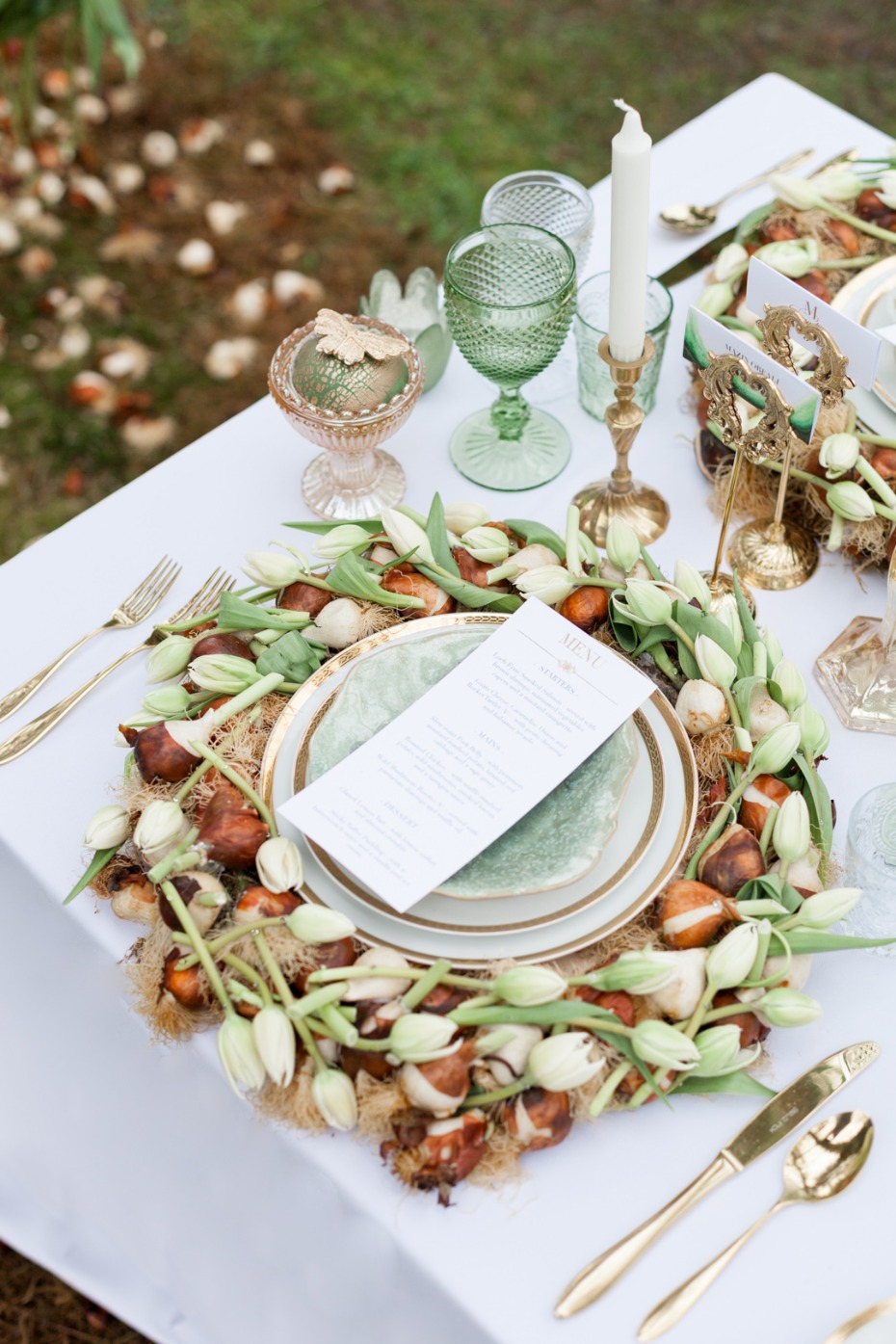 Elegant table setting with floral wreath and golden cutlery