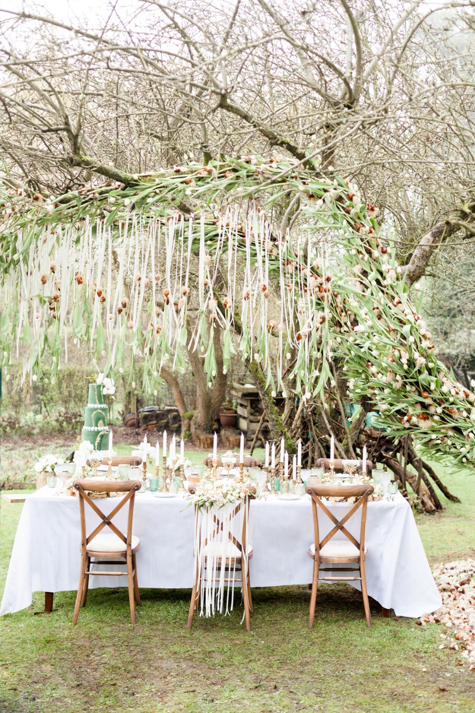 Elegant outdoor wedding table setting under a whimsical tree canopy