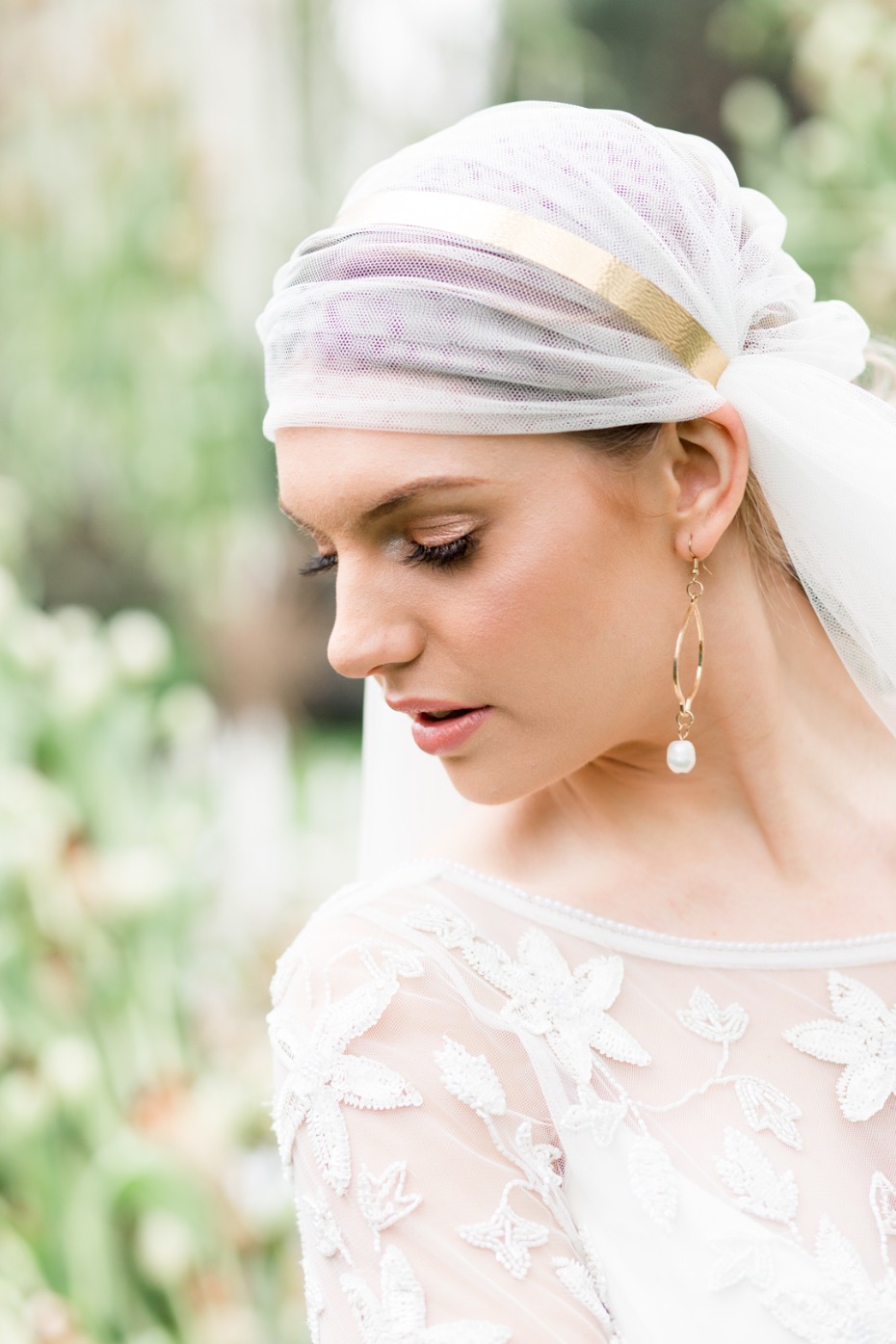 Elegant bride wearing a veil and pearl earrings, soft focus background