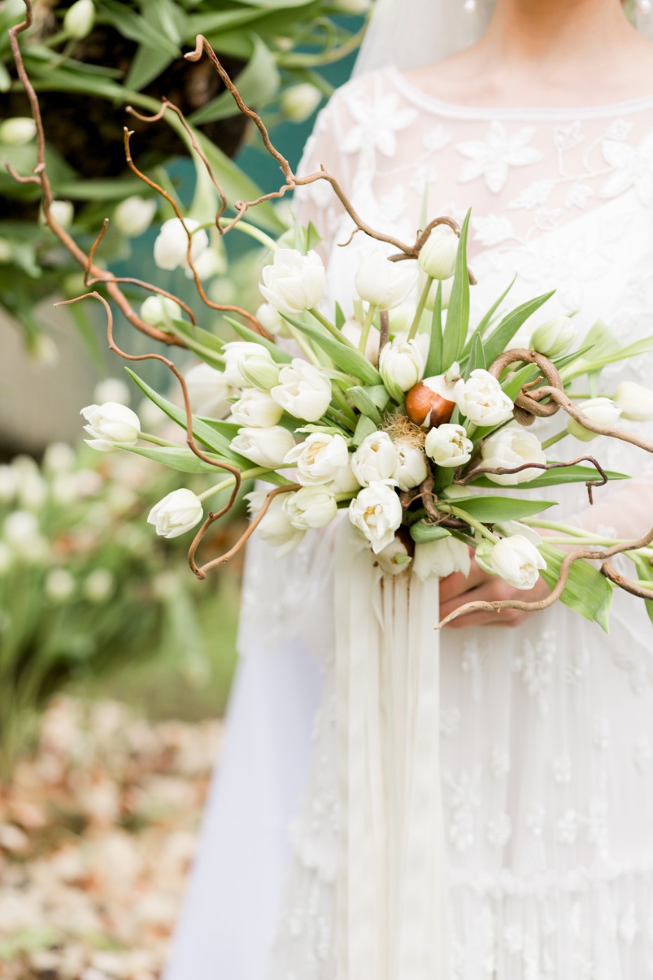 Bride holding a white tulip bouquet decorated with branches