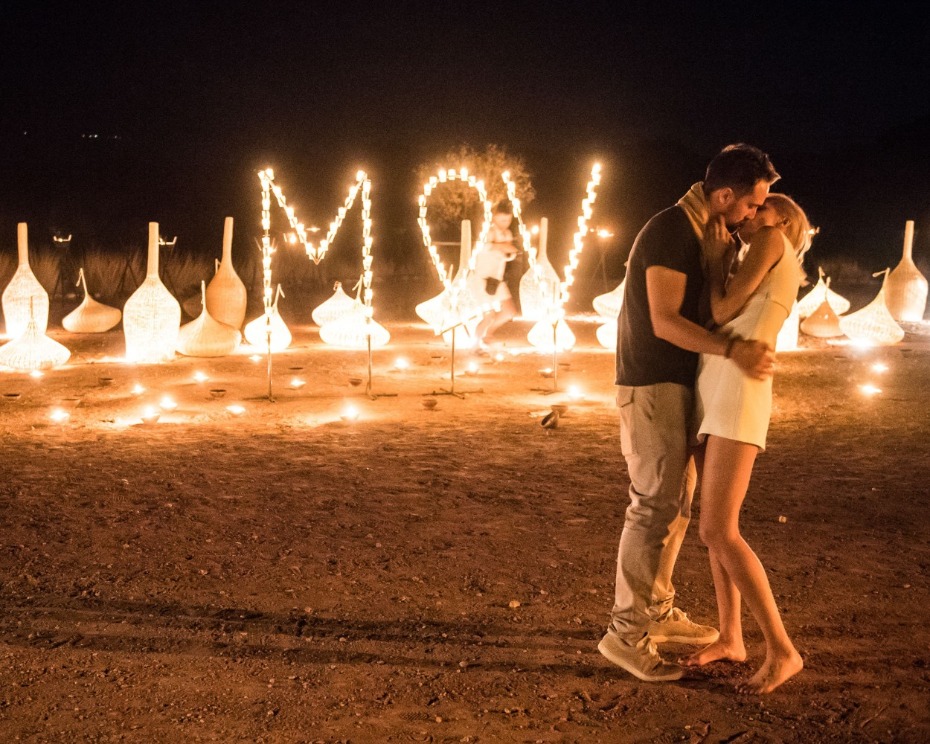 Romantic couple kissing under LOVE lights at night