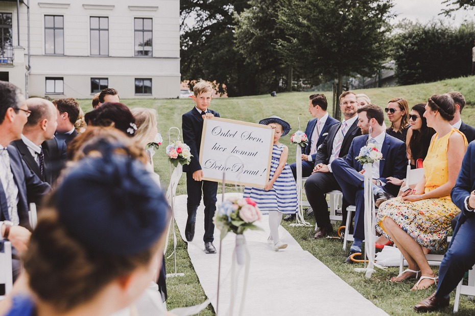 Children lead the way during a wedding ceremony with a sign