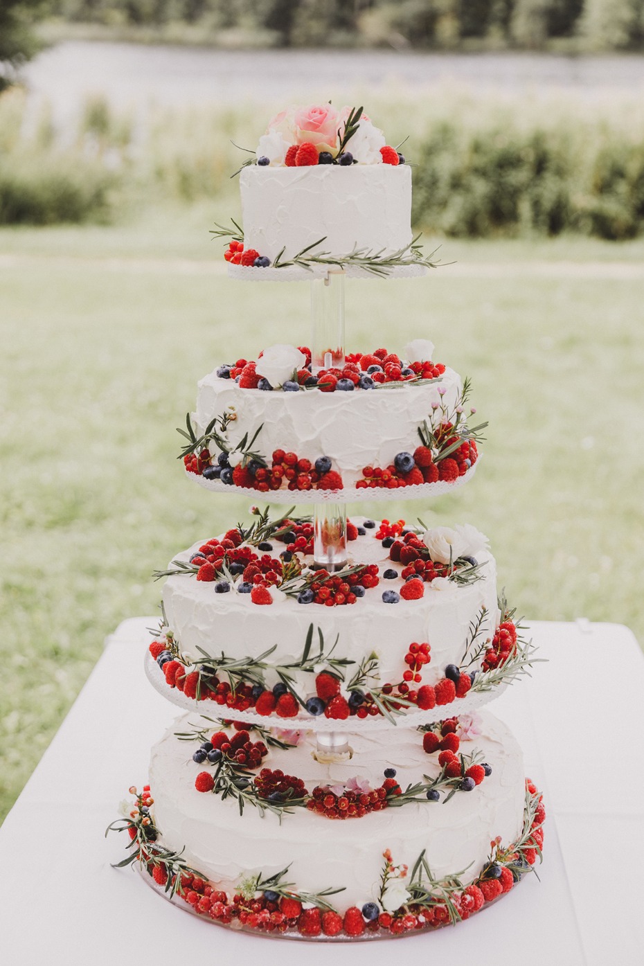 Four-tiered wedding cake decorated with berries and floral accents