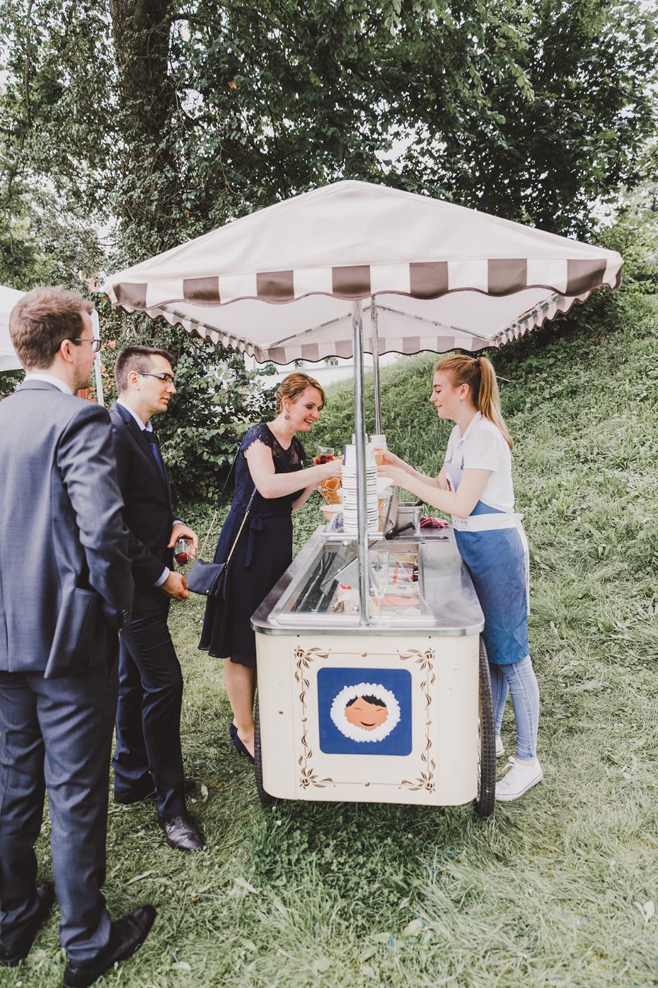 People enjoying ice cream from a vintage cart at an outdoor event