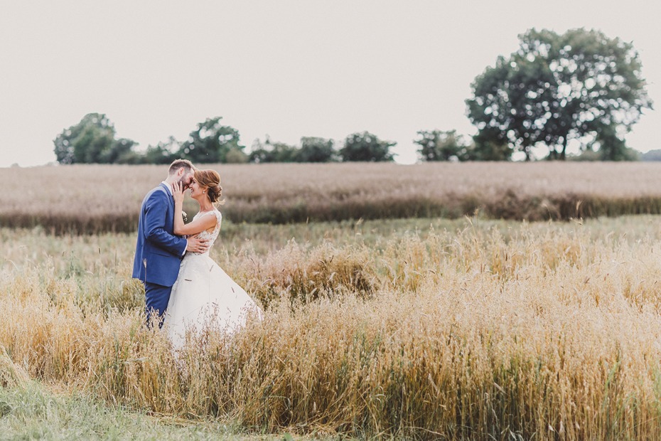 Bride and groom share a tender moment in a golden wheat field