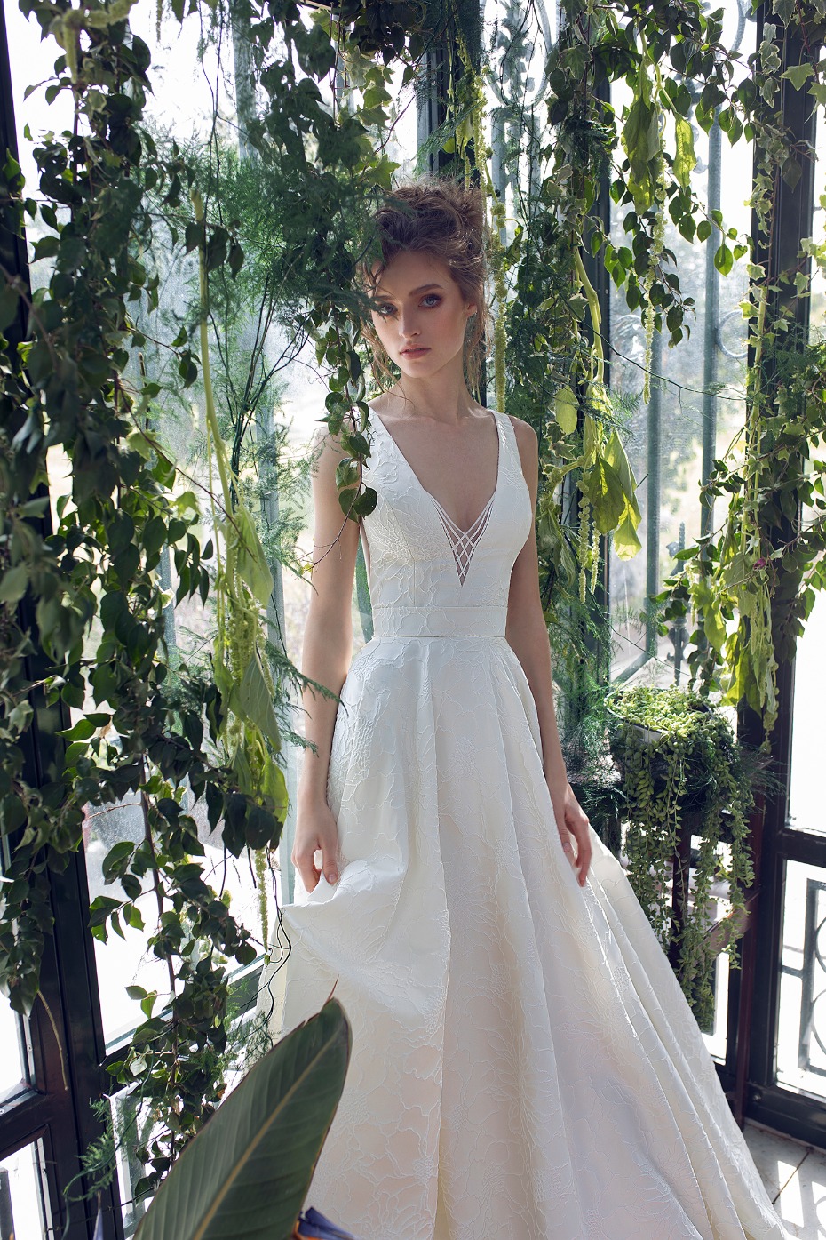 Elegant bride in white dress surrounded by lush green foliage