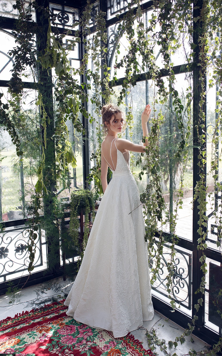 Elegant bride in white dress surrounded by lush greenery