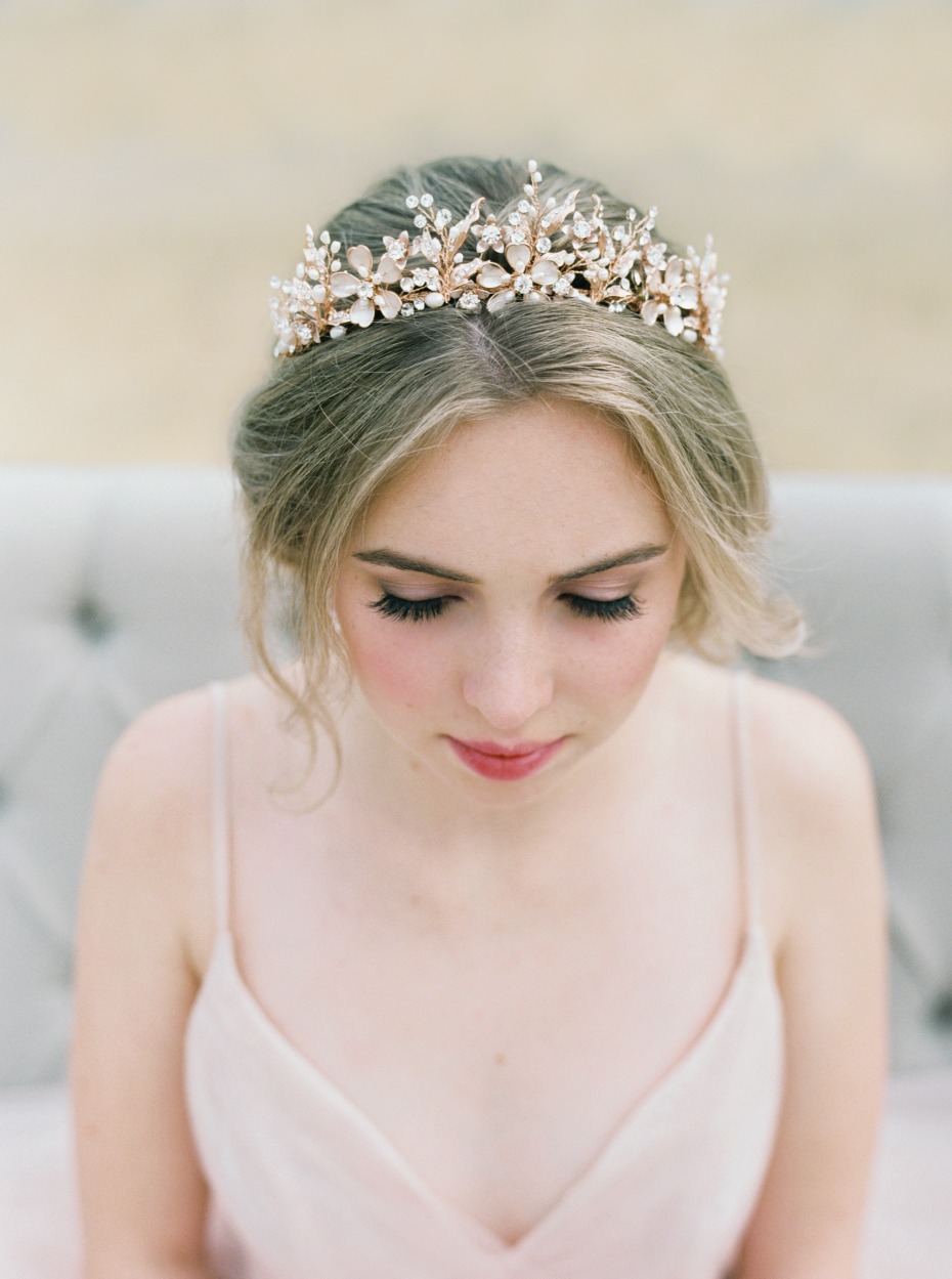 A beautiful bride wearing a floral crown looks down, soft and elegant