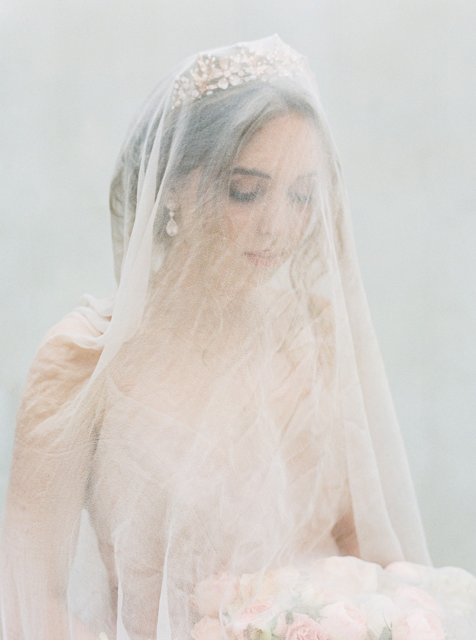 Elegant bride wearing a veil and floral crown, holding a bouquet
