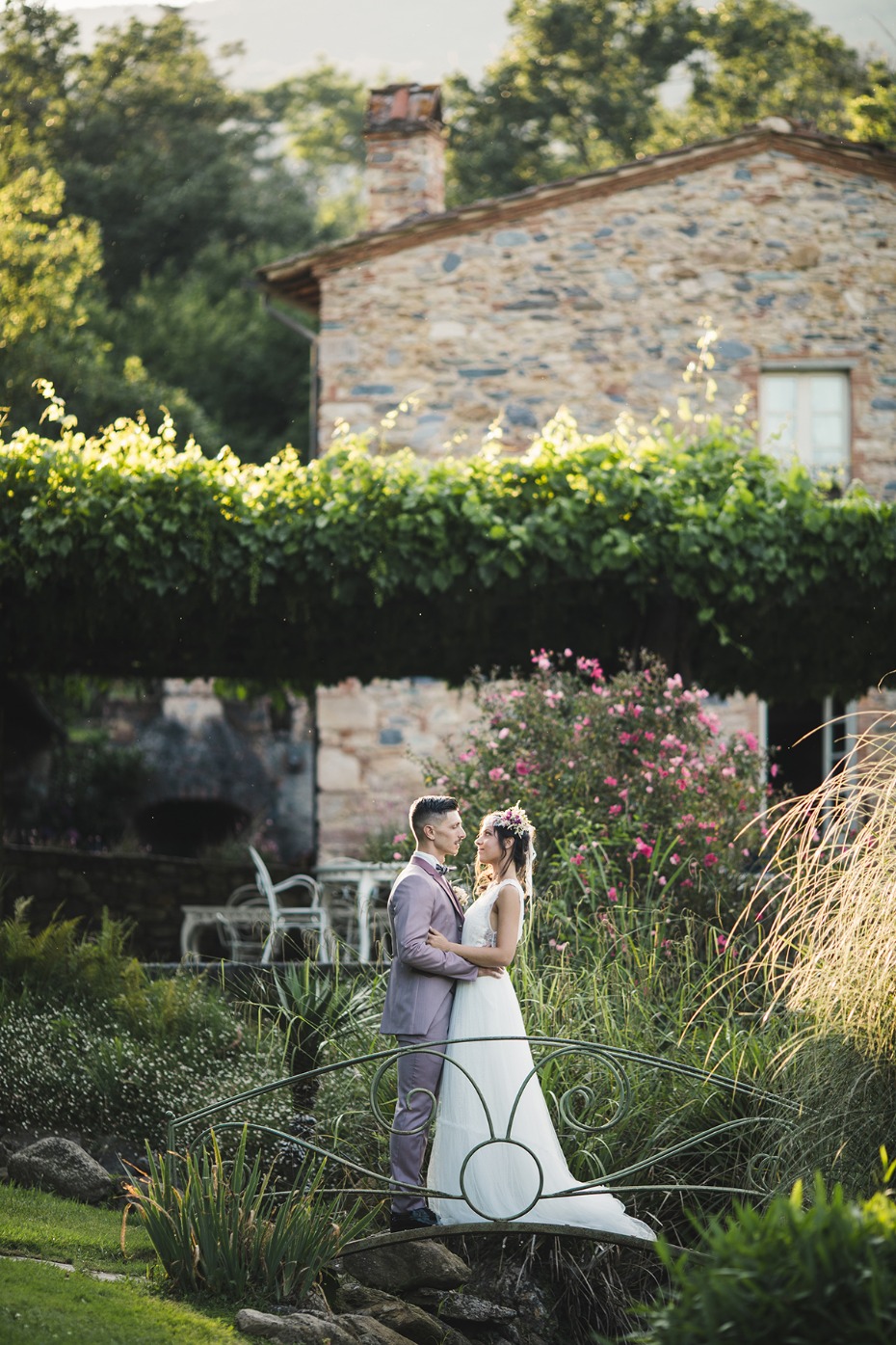 Bride and groom embracing on a bridge in garden setting