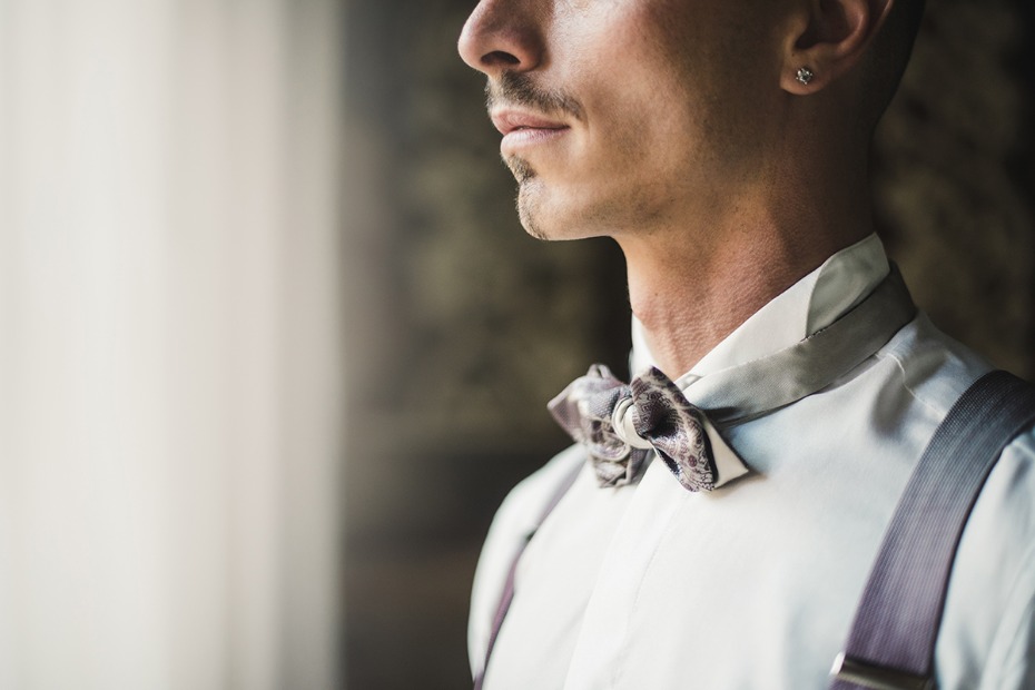 Groom in white shirt suspenders and paisley bow tie
