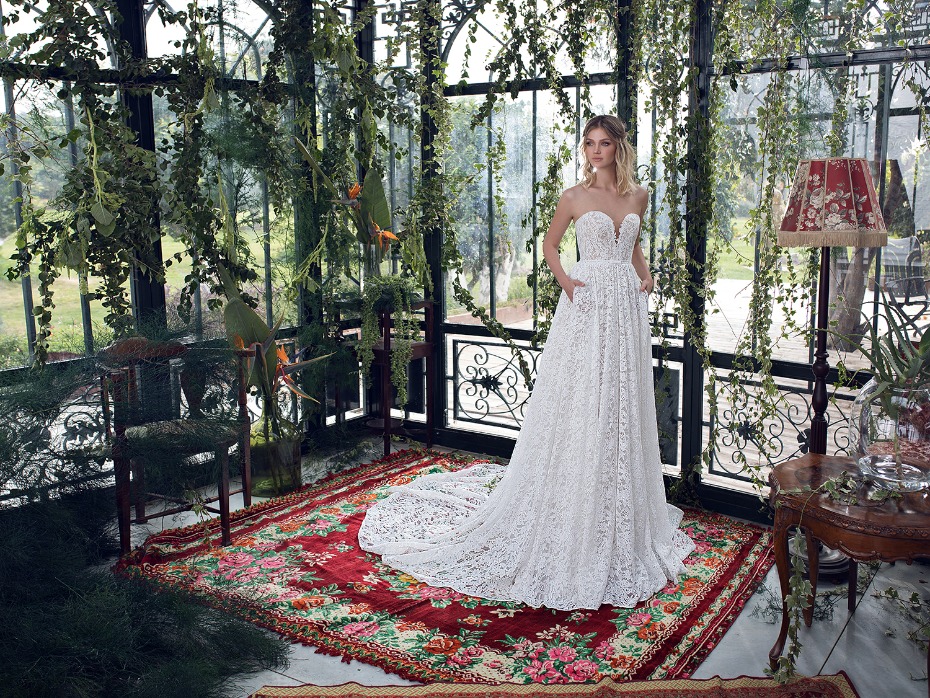 Elegant bride in lace gown poses in greenhouse setting