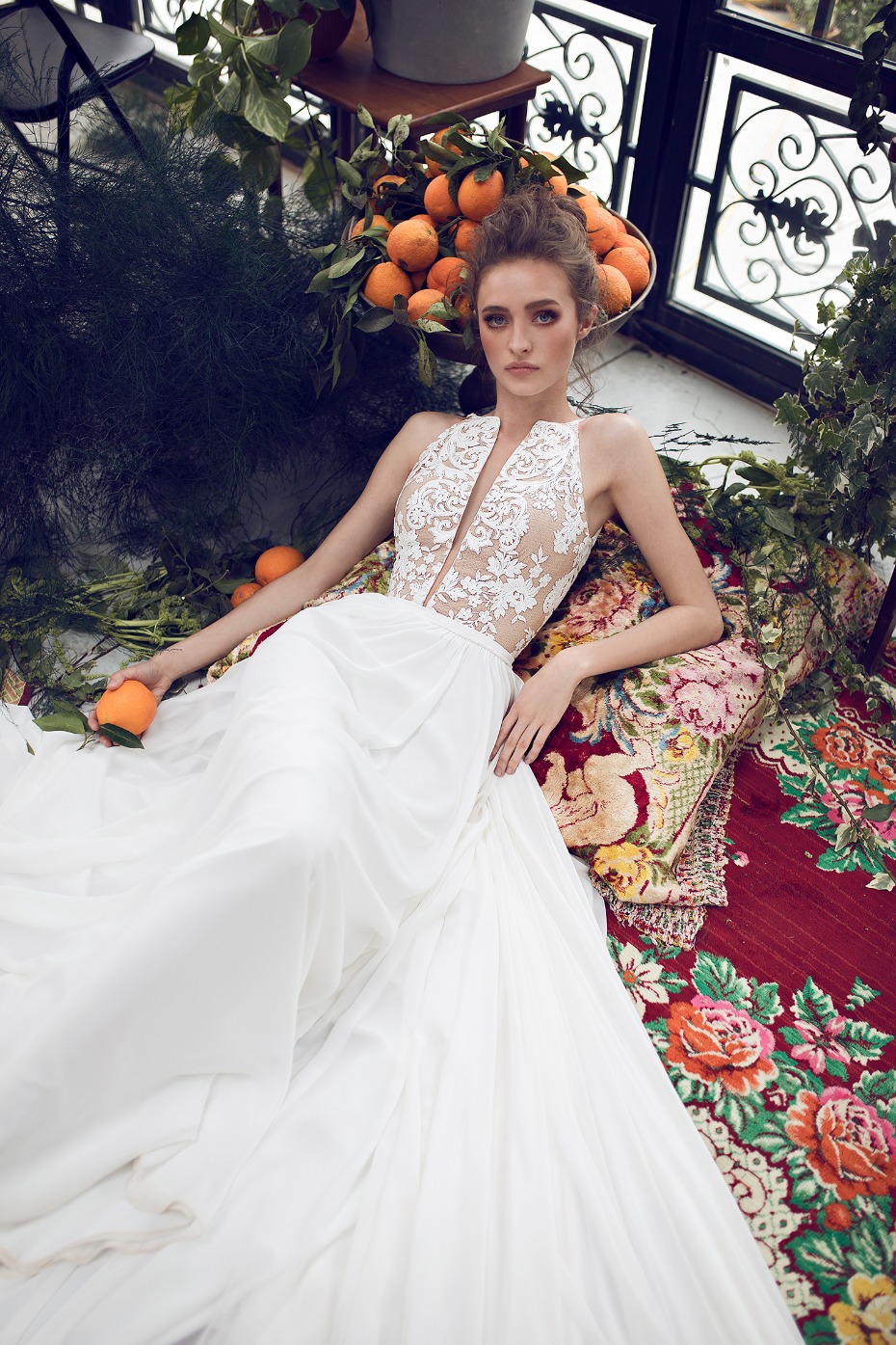 Elegant bride in white dress posing with oranges and flowers