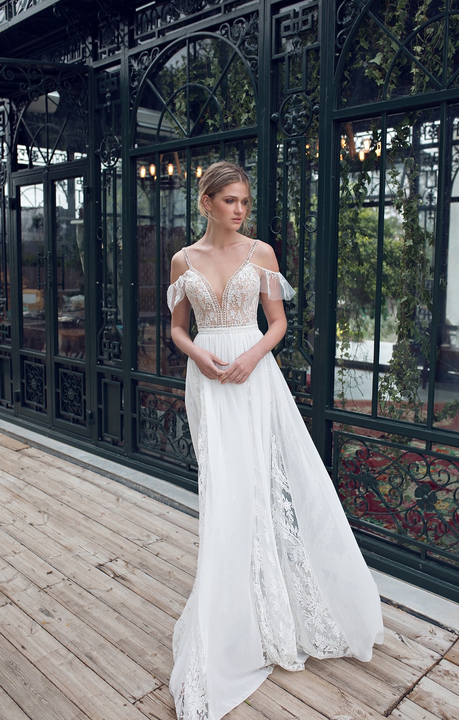 Elegant bride in a flowing white wedding dress stands gracefully